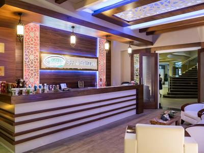 Eleganter Hotellobbybereich mit Holztheke, Sitzgelegenheiten und beleuchteten Deckenakzenten.