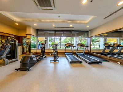 Moderner Fitnessraum mit Laufbändern, Trainingsgeräten und großen Fenstern mit Blick auf Außenbereich.