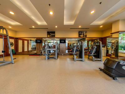 Hell beleuchteter Hotel-Fitnessraum mit verschiedenen Trainingsgeräten und großen Fenstern.