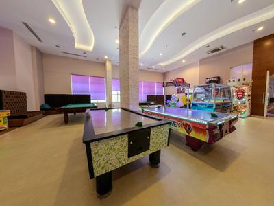 Innenraum einer Spielehalle mit Billardtisch, Airhockey und bunten Spielgeräten in hellem Raum.
