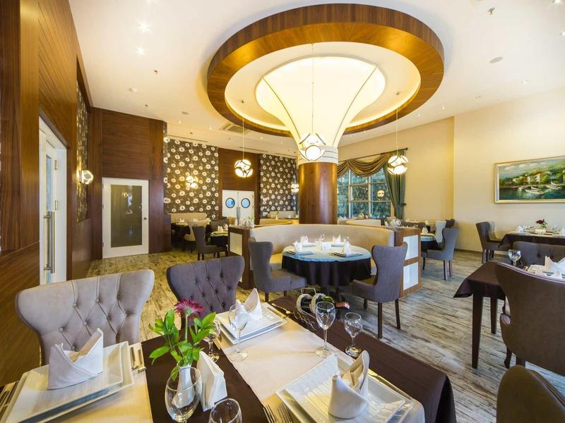 Elegantní jídelna s prostřenými stoly, křesly a moderním zařízením.