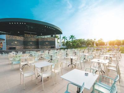 Espace extérieur vide d'un café moderne avec des tables et chaises blanches au coucher du soleil.