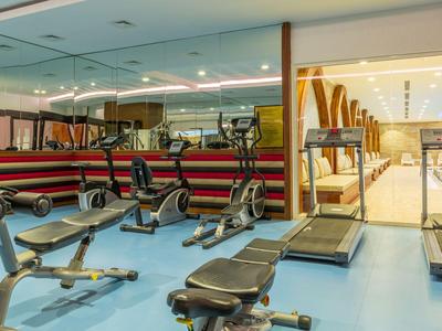 Interno di una palestra moderna con panche per pesi e tapis roulant in un hotel.