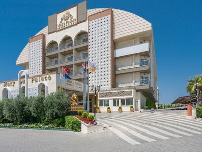 Edificio di hotel moderno con facciate bianche, palme e cielo azzurro terso sullo sfondo.