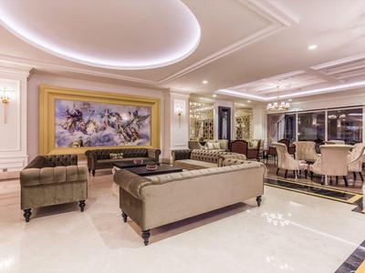 Zona lounge di un elegante hotel con divani beige, opera d'arte moderna e illuminazione elegante.
