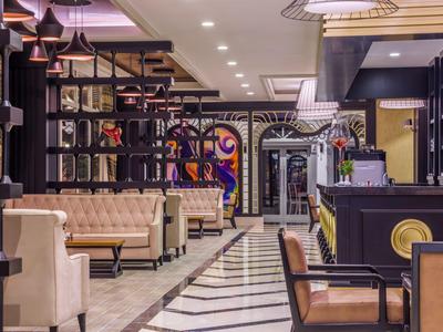 Moderna hall d'hotel con comode sedute, scaffali decorativi e bancone elegante.