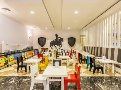 Area bambini colorata in un hotel con piccoli tavoli e sedie.
