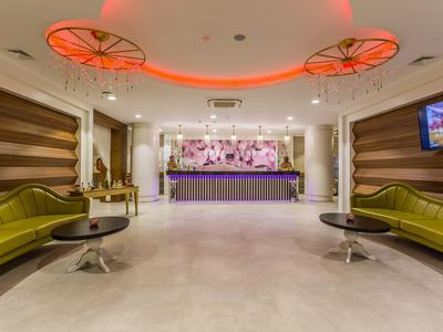 Hall dell'hotel moderno con panchine verdi e reception illuminata.