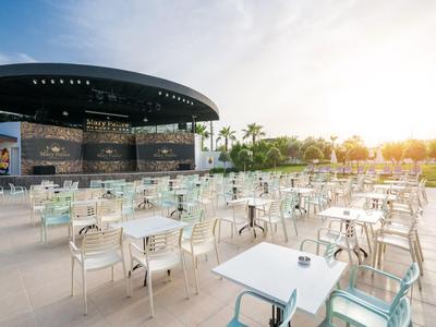 Moderna terrazza all'aperto con sedie e tavoli trasparenti davanti a un palco all'aperto al tramonto.
