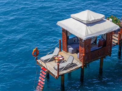 Un pontile di legno roccioso con una piccola capanna costruita sopra il mare e una scala che conduce all'acqua.