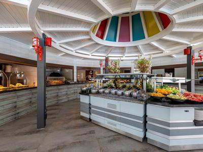 Lobby dell'hotel moderna con area buffet e pannelli colorati sul soffitto in vetro.