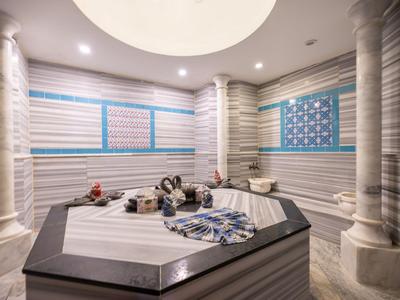 Hammam moderno con pareti in marmo, piattaforma centrale e elementi di design orientale.