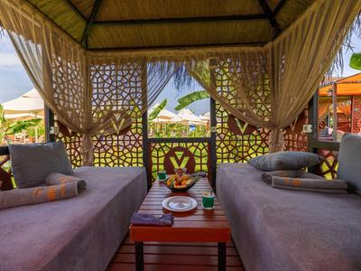 Lounge accogliente con tende leggere, divano e decorazioni tropicali per relax in vacanza.