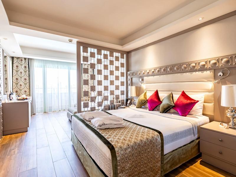 Habitación de hotel moderna con cama grande, cojines de colores y suelo de madera.