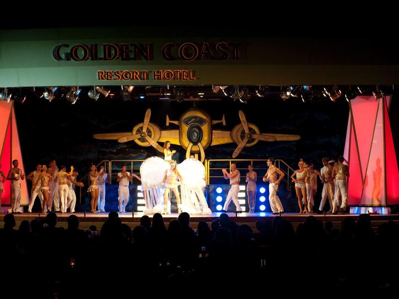 Actuación en escenario con bailarines y cantantes bajo un cartel de Golden Tulip en un hotel.