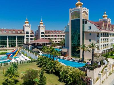 Large luxury hotel with pools, sun umbrellas, water slides, and garden by the sea.