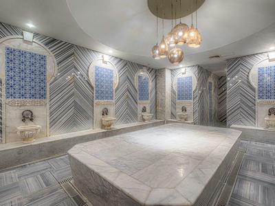 Luxurious spa room with marble central platform, patterned walls, and ambient lighting fixtures.