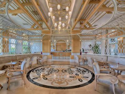 Luxury hotel lobby with circular seating, intricate ceiling, and marble floor with ornate design.