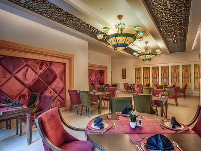 Elegant dining room with round tables, red chairs, and decorative ceiling lights.