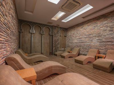 Cozy spa room with curved lounge chairs, stone walls, and skylights for natural light.