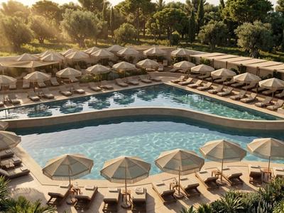 Large hotel pool with sun loungers and umbrellas surrounded by palm trees at sunset.