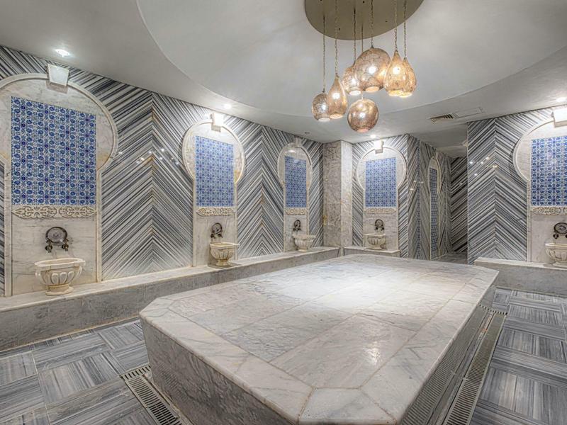 Luxurious spa room with marble central platform, patterned walls, and ambient lighting fixtures.