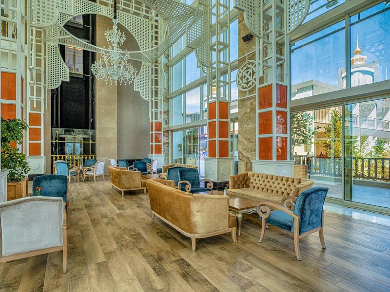 Spacious hotel lobby with elegant seating, large windows, and warm wooden flooring.