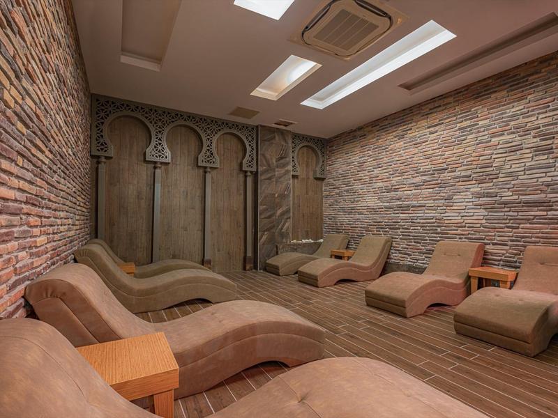 Cozy spa room with curved lounge chairs, stone walls, and skylights for natural light.