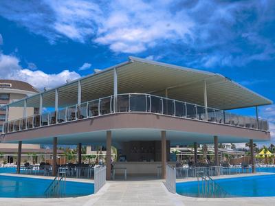 Moderní dvoupatrová bazénová zóna s terasou na slunění a modrou oblohou v hotelovém resortu