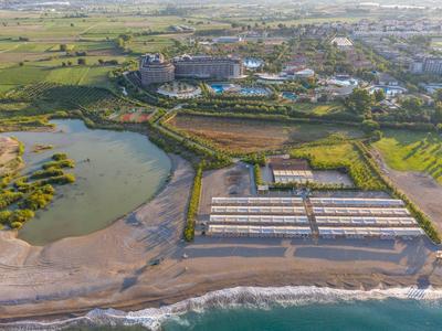 Letecký pohled na hotel u pláže s parkovištěm, sousedním rybníkem a zelenými poli