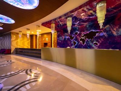 Moderní hotelová recepce s zakřivenou přepážkou a barevným nástěnným designem.