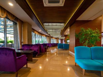 Moderní hotelová lobby s fialovými a modrými křesly a velkými okny.