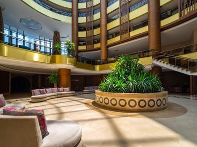 Velký hotelový lobby prostor s polstrovaným sezením a centrální dekorací ze zeleně
