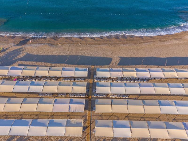 Letecký pohled na organizovanou pláž s řadami slunečníků u moře
