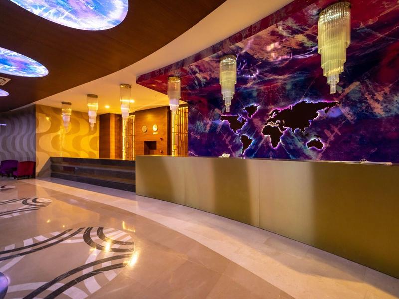 Moderní hotelová lobby s zakřivenou recepcí a barevným nástěnným uměním.