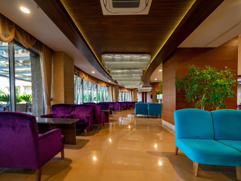 Moderní hotelová lobby s fialovými a modrými křesly a velkými okny.