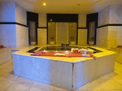 Achtkantig binnenjacuzzi met rode handdoeken in een betegelde spa kamer met zachte verlichting.