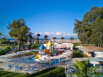 Waterpark met meerdere glijbanen, zwembaden en omliggend groen landschap onder een heldere lucht.