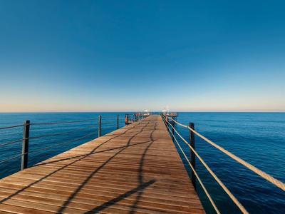 Houten pier over kalme zee onder heldere blauwe lucht