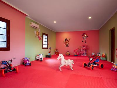 Kleurrijke speelkamer met rode muren, speelgoed en twee ramen.