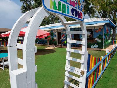 Kleurrijke toegangspoort tot een mini club met cartoonfiguren en zitplaatsen buiten.