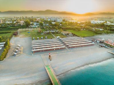 Zonsondergang boven een strandresort met pieren die uitkomen in kalm blauw water en groene velden daarachter.