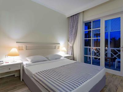 Moderne hotelkamer met tweepersoonsbed, nachtkastjes en groot raam met uitzicht op terras