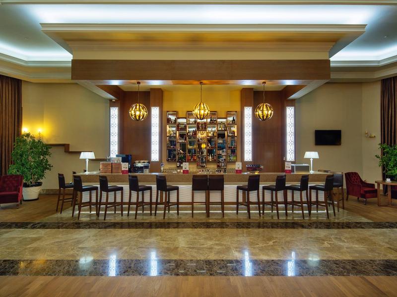 Moderne hotel lobby met een lange houten receptiebalie, stoelen en warme verlichting.