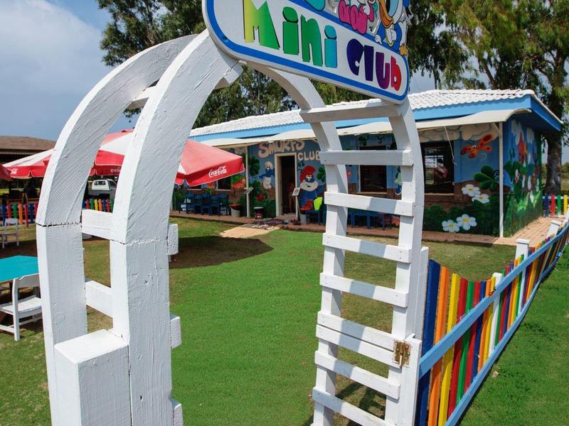 Kleurrijke ingang boog met tekenfilmfiguren verwelkomt gasten in een speelse buitenruimte.