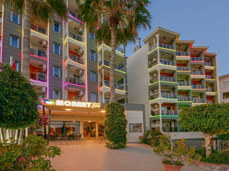 Meerdere verdiepingen tellend hotel met aangelegde ingang en palmbomen onder heldere lucht