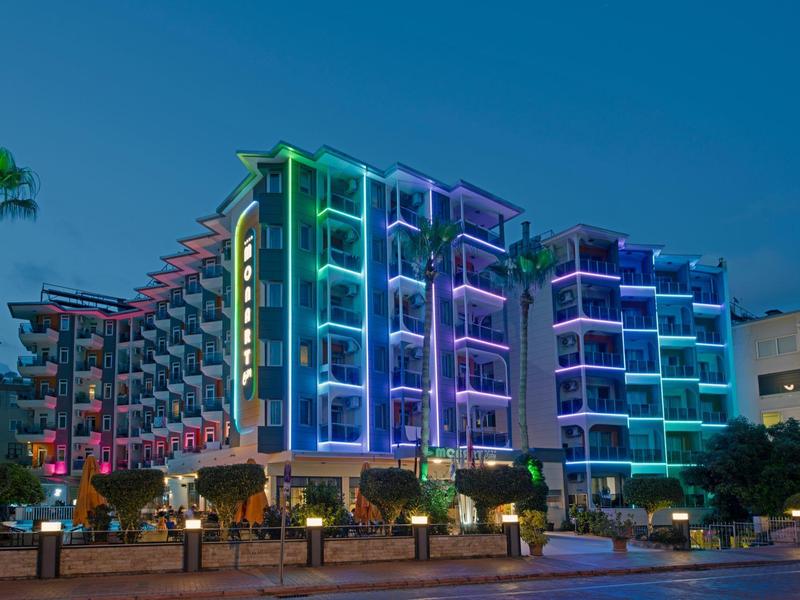 Meerverdieping hotel 's nachts met kleurrijke neonlichten aan de gevel.