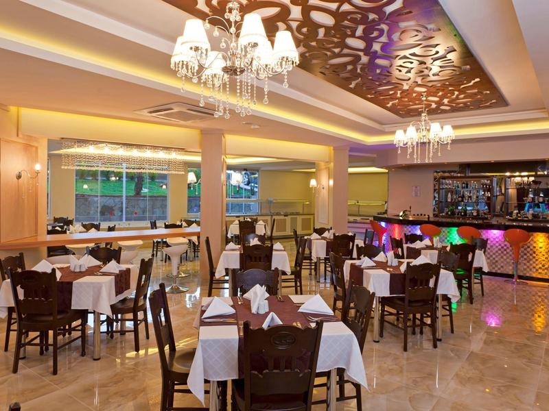 Elegant restaurant met gedekte tafels, kroonluchters en bar op de achtergrond.