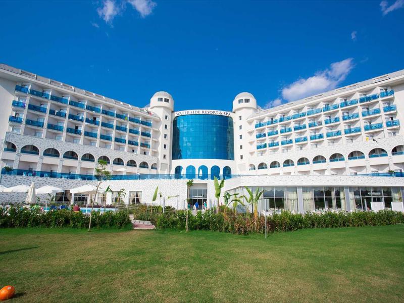 Hôtel blanc moderne avec pelouse verte sous un ciel bleu clair.