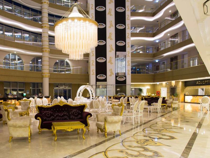 Hall d'hôtel spacieux avec lustre élégant et sièges dorés.